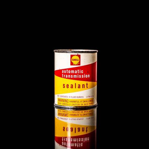 Vintage Shell oil cans with red and yellow branding from the 1900-1920 old logo Vintage Shell oil cans from 1900-19255, featuring the old logo. The photo showcases an antique tin red with yellow accents, displaying the historic Shell emblem. Shot in a studio against a solid black background