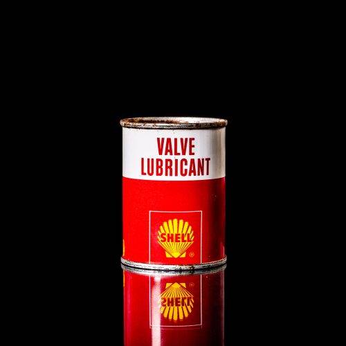 Vintage Shell oil cans with red and yellow branding from the 1900-1920 old logo Vintage Shell oil cans from 1900-19255, featuring the old logo. The photo showcases an antique tin red with yellow accents, displaying the historic Shell emblem. Shot in a studio against a solid black background