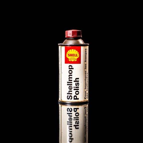 Vintage Shell oil cans with red and yellow branding from the 1900-1920 old logo Vintage Shell oil cans from 1900-19255, featuring the old logo. The photo showcases an antique tin red with yellow accents, displaying the historic Shell emblem. Shot in a studio against a solid black background