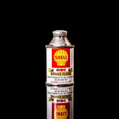 Vintage Shell oil cans with red and yellow branding from the 1900-1920 old logo Vintage Shell oil cans from 1900-19255, featuring the old logo. The photo showcases an antique tin red with yellow accents, displaying the historic Shell emblem. Shot in a studio against a solid black background