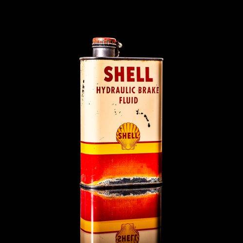 Vintage Shell oil cans with red and yellow branding from the 1900-1920 old logo Vintage Shell oil cans from 1900-19255, featuring the old logo. The photo showcases an antique tin red with yellow accents, displaying the historic Shell emblem. Shot in a studio against a solid black background