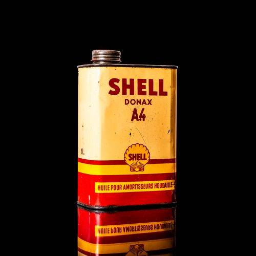 Vintage Shell oil cans with red and yellow branding from the 1900-1920 old logo Vintage Shell oil cans from 1900-19255, featuring the old logo. The photo showcases an antique tin red with yellow accents, displaying the historic Shell emblem. Shot in a studio against a solid black background