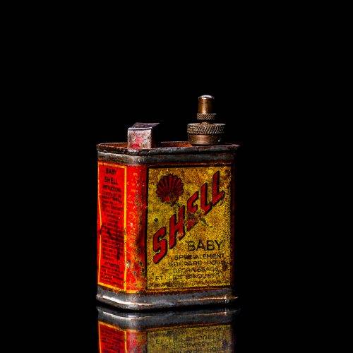 Rare and unique vintage mini Shell oil can Handy oil from 1900–1950 with red and yellow accents, featuring the classic Shell logo. This small antique tin is displayed in a studio setting against a solid black background. Handy oil cans