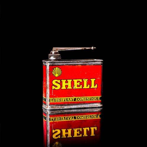 Rare and unique vintage mini Shell oil can Handy oil from 1900–1950 with red and yellow accents, featuring the classic Shell logo. This small antique tin is displayed in a studio setting against a solid black background. Handy oil cans