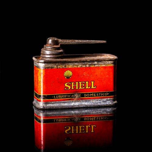 Rare and unique vintage mini Shell oil can Handy oil from 1900–1950 with red and yellow accents, featuring the classic Shell logo. This small antique tin is displayed in a studio setting against a solid black background. Handy oil cans