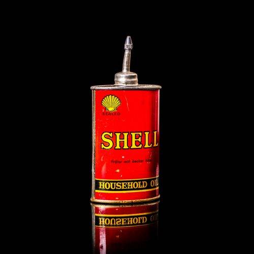 Rare and unique vintage mini Shell oil can Handy oil from 1900–1950 with red and yellow accents, featuring the classic Shell logo. This small antique tin is displayed in a studio setting against a solid black background. Handy oil cans