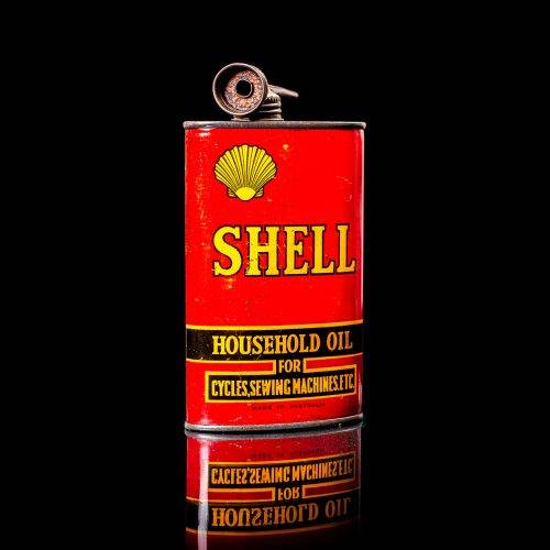 Rare and unique vintage mini Shell oil can Handy oil from 1900–1950 with red and yellow accents, featuring the classic Shell logo. This small antique tin is displayed in a studio setting against a solid black background. Handy oil cans