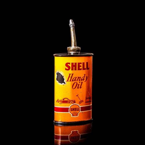Rare and unique vintage mini Shell oil can Handy oil from 1900–1950 with red and yellow accents, featuring the classic Shell logo. This small antique tin is displayed in a studio setting against a solid black background. Handy oil cans