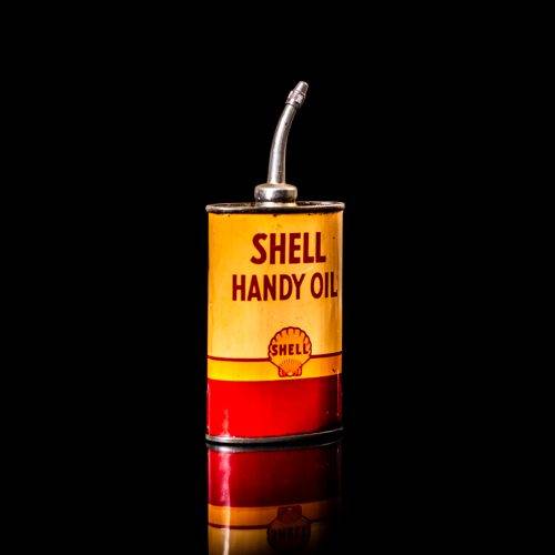 Vintage Shell oil cans with red and yellow branding from the 1900-1920 old logo Vintage Shell oil cans from 1900-19255, featuring the old logo. The photo showcases an antique tin red with yellow accents, displaying the historic Shell emblem. Shot in a studio against a solid black background