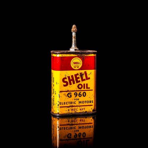 Vintage Shell oil cans with red and yellow branding from the 1900-1920 old logo Vintage Shell oil cans from 1900-19255, featuring the old logo. The photo showcases an antique tin red with yellow accents, displaying the historic Shell emblem. Shot in a studio against a solid black background