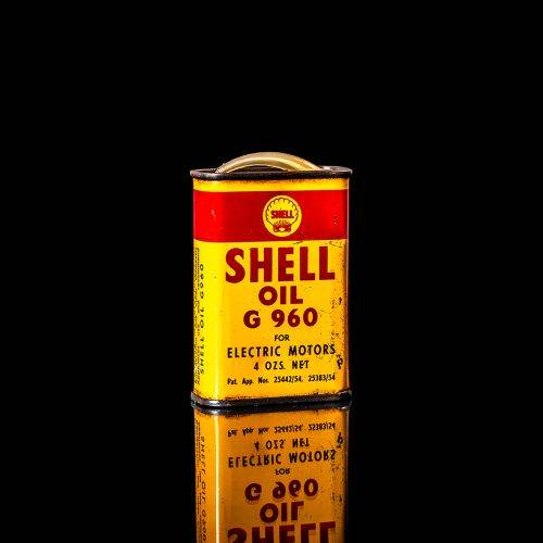 Rare and unique vintage mini Shell oil can Handy oil from 1900–1950 with red and yellow accents, featuring the classic Shell logo. This small antique tin is displayed in a studio setting against a solid black background. Handy oil cans