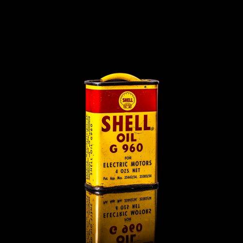 Rare and unique vintage mini Shell oil can Handy oil from 1900–1950 with red and yellow accents, featuring the classic Shell logo. This small antique tin is displayed in a studio setting against a solid black background. Handy oil cans