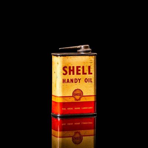 Rare and unique vintage mini Shell oil can Handy oil from 1900–1950 with red and yellow accents, featuring the classic Shell logo. This small antique tin is displayed in a studio setting against a solid black background. Handy oil cans