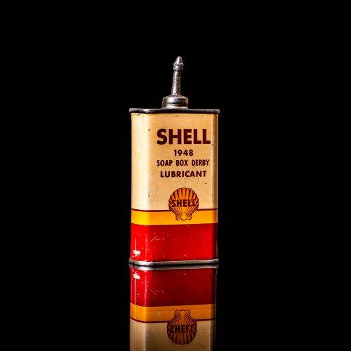Rare and unique vintage mini Shell oil can Handy oil from 1900–1950 with red and yellow accents, featuring the classic Shell logo. This small antique tin is displayed in a studio setting against a solid black background. Handy oil cans