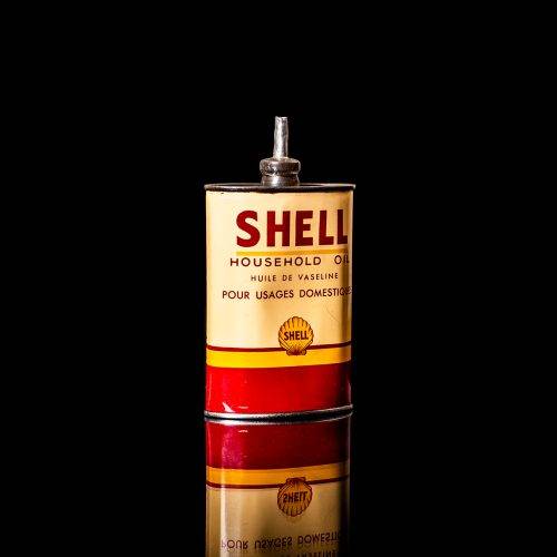 Vintage Shell oil cans with red and yellow branding from the 1900-1920 old logo Vintage Shell oil cans from 1900-19255, featuring the old logo. The photo showcases an antique tin red with yellow accents, displaying the historic Shell emblem. Shot in a studio against a solid black background
