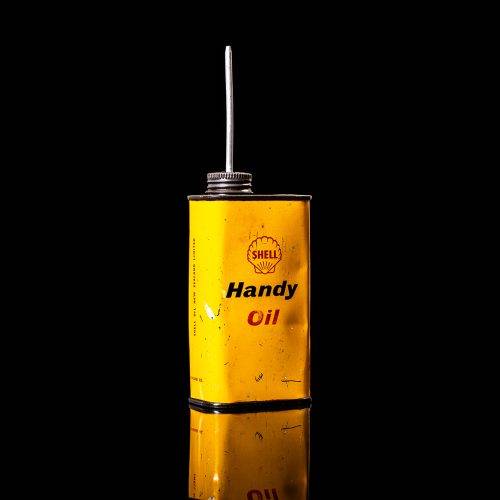 Vintage Shell oil cans with red and yellow branding from the 1900-1920 old logo Vintage Shell oil cans from 1900-19255, featuring the old logo. The photo showcases an antique tin red with yellow accents, displaying the historic Shell emblem. Shot in a studio against a solid black background