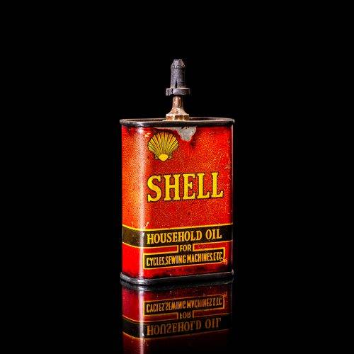 Vintage Shell oil cans with red and yellow branding from the 1900-1920 old logo Vintage Shell oil cans from 1900-19255, featuring the old logo. The photo showcases an antique tin red with yellow accents, displaying the historic Shell emblem. Shot in a studio against a solid black background