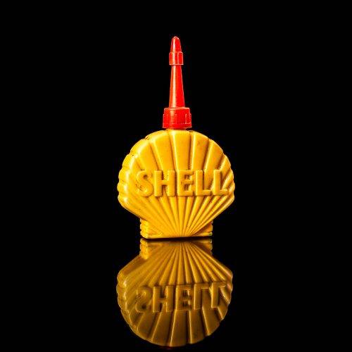 Vintage Shell oil cans with red and yellow branding from the 1900-1920 old logo Vintage Shell oil cans from 1900-19255, featuring the old logo. The photo showcases an antique tin red with yellow accents, displaying the historic Shell emblem. Shot in a studio against a solid black background