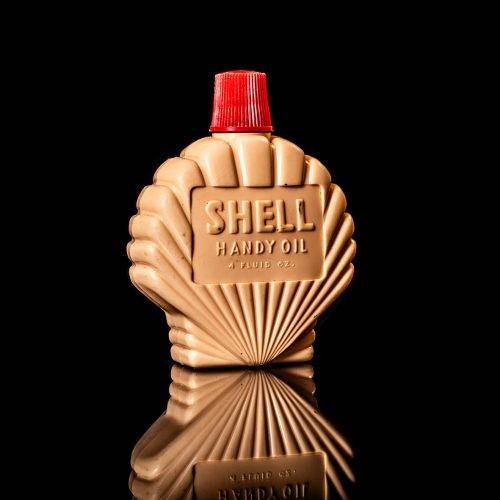 Rare and unique vintage mini Shell oil can Handy oil from 1900–1950 with red and yellow accents, featuring the classic Shell logo. This small antique tin is displayed in a studio setting against a solid black background." Handy oil cans