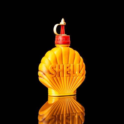 Vintage Shell oil cans with red and yellow branding from the 1900-1920 old logo Vintage Shell oil cans from 1900-19255, featuring the old logo. The photo showcases an antique tin red with yellow accents, displaying the historic Shell emblem. Shot in a studio against a solid black background