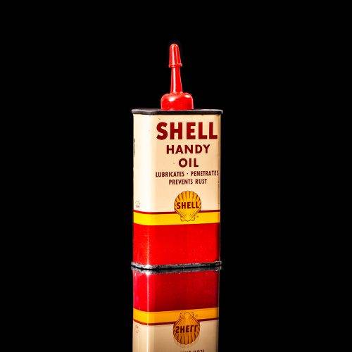 Rare and unique vintage mini Shell oil can Handy oil from 1900–1950 with red and yellow accents, featuring the classic Shell logo. This small antique tin is displayed in a studio setting against a solid black background." Handy oil cans