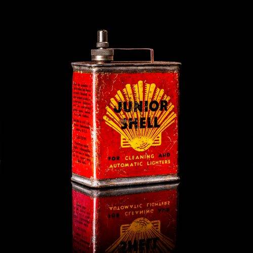 Rare and unique vintage mini Shell oil can from 1900–1950 with red and yellow accents, featuring the classic Shell logo. This small antique tin is displayed in a studio setting against a solid black background. lighter fluid shell cans