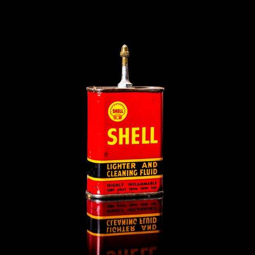 Rare and unique vintage mini Shell oil can from 1900–1950 with red and yellow accents, featuring the classic Shell logo. This small antique tin is displayed in a studio setting against a solid black background. lighter fluid shell cans