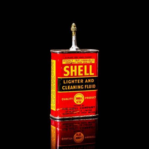 Rare and unique vintage mini Shell oil can from 1900–1950 with red and yellow accents, featuring the classic Shell logo. This small antique tin is displayed in a studio setting against a solid black background. lighter fluid shell cans