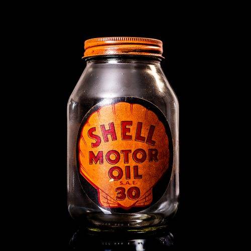 Vintage Shell oil cans with red and yellow branding from the 1900-1920 old logo Vintage Shell oil cans from 1900-19255, featuring the old logo. The photo showcases an antique tin red with yellow accents, displaying the historic Shell emblem. Shot in a studio against a solid black background