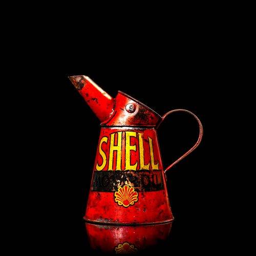 Rare and unique vintage Shell oil pourer from 1900–1950 with red and yellow accents, featuring the classic Shell logo. This antique metal spout can is displayed in a studio setting against a solid black background.