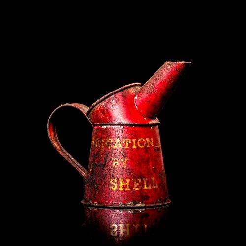 Vintage Shell oil cans with red and yellow branding from the 1900-1920 old logo Vintage Shell oil cans from 1900-19255, featuring the old logo. The photo showcases an antique tin red with yellow accents, displaying the historic Shell emblem. Shot in a studio against a solid black background