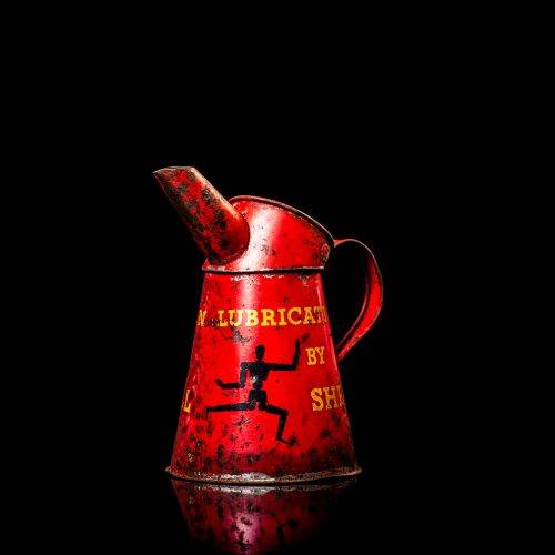 Vintage Shell oil cans with red and yellow branding from the 1900-1920 old logo Vintage Shell oil cans from 1900-19255, featuring the old logo. The photo showcases an antique tin red with yellow accents, displaying the historic Shell emblem. Shot in a studio against a solid black background