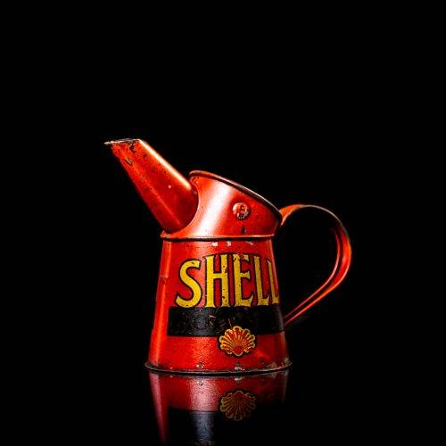 Rare and unique vintage Shell oil pourer from 1900–1950 with red and yellow accents, featuring the classic Shell logo. This antique metal spout can is displayed in a studio setting against a solid black background.