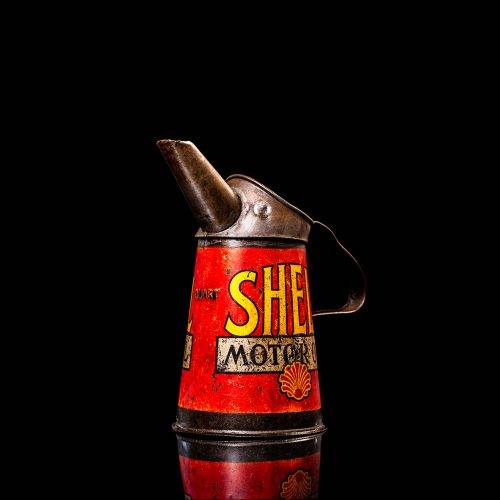 Rare and unique vintage Shell oil pourer from 1900–1950 with red and yellow accents, featuring the classic Shell logo. This antique metal spout can is displayed in a studio setting against a solid black background.