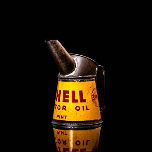 Vintage Shell oil cans with red and yellow branding from the 1900-1920 old logo Vintage Shell oil cans from 1900-19255, featuring the old logo. The photo showcases an antique tin red with yellow accents, displaying the historic Shell emblem. Shot in a studio against a solid black background