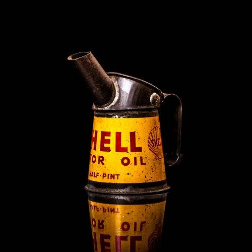 Vintage Shell oil cans with red and yellow branding from the 1900-1920 old logo Vintage Shell oil cans from 1900-19255, featuring the old logo. The photo showcases an antique tin red with yellow accents, displaying the historic Shell emblem. Shot in a studio against a solid black background