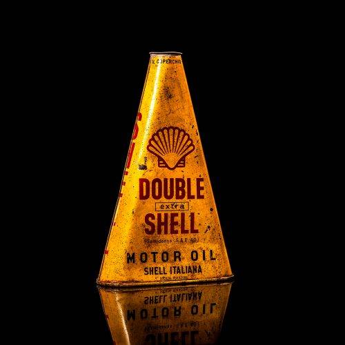 Extremely rare and unique vintage Shell triangular oil can from 1900–1950, featuring red and yellow accents and the classic Shell logo, including a rare shell branding. This antique three-sided tin is displayed in a studio setting against a solid black background.