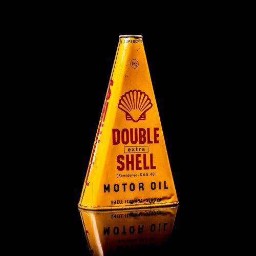 Vintage Shell oil cans with red and yellow branding from the 1900-1920 old logo Vintage Shell oil cans from 1900-19255, featuring the old logo. The photo showcases an antique tin red with yellow accents, displaying the historic Shell emblem. Shot in a studio against a solid black background