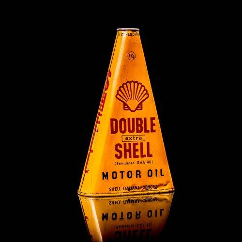 Extremely rare and unique vintage Shell triangular oil can from 1900–1950, featuring red and yellow accents and the classic Shell logo, including a rare shell branding. This antique three-sided tin is displayed in a studio setting against a solid black background.