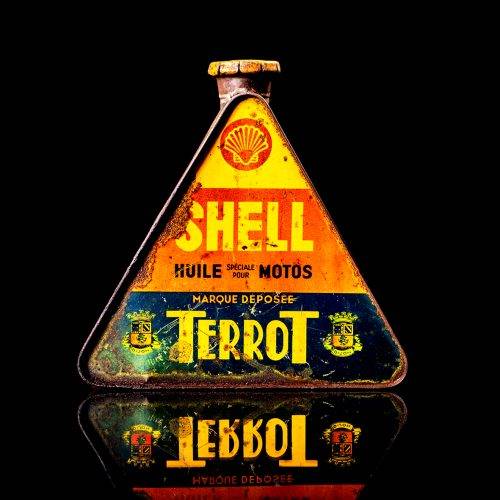 Extremely rare and unique vintage Shell triangular oil can from 1900–1950, featuring red and yellow accents and the classic Shell logo, including a rare shell branding. This antique three-sided tin is displayed in a studio setting against a solid black background.