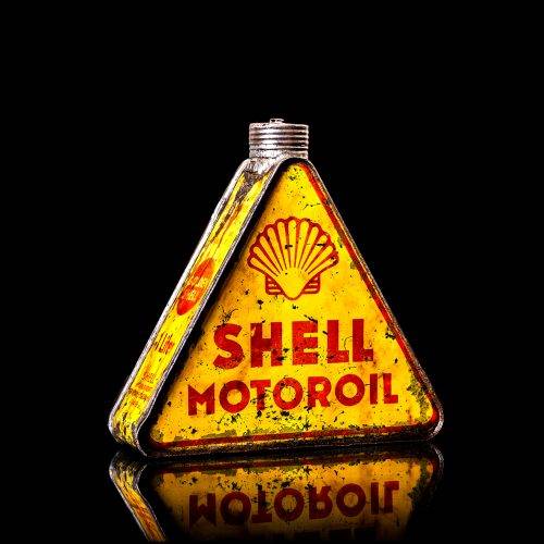 Vintage Shell oil cans with red and yellow branding from the 1900-1920 old logo Vintage Shell oil cans from 1900-19255, featuring the old logo. The photo showcases an antique tin red with yellow accents, displaying the historic Shell emblem. Shot in a studio against a solid black background