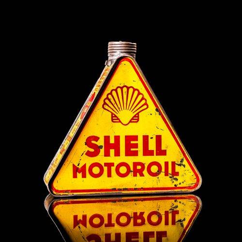 Extremely rare and unique vintage Shell triangular oil can from 1900–1950, featuring red and yellow accents and the classic Shell logo, including a rare shell branding. This antique three-sided tin is displayed in a studio setting against a solid black background.
