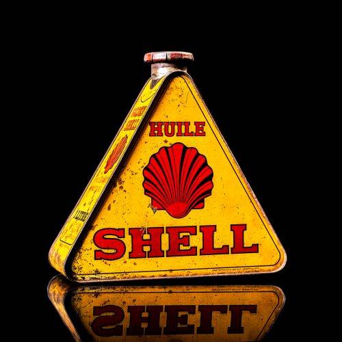 Extremely rare and unique vintage Shell triangular oil can from 1900–1950, featuring red and yellow accents and the classic Shell logo, including a rare shell branding. This antique three-sided tin is displayed in a studio setting against a solid black background.