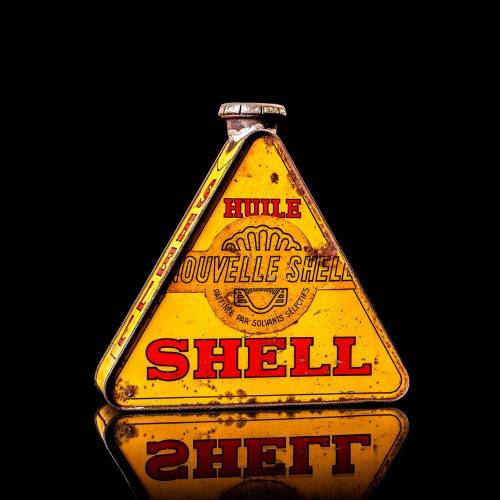 Extremely rare and unique vintage Shell triangular oil can from 1900–1950, featuring red and yellow accents and the classic Shell logo, including a rare shell branding. This antique three-sided tin is displayed in a studio setting against a solid black background.