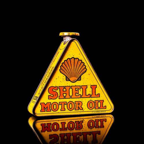 Vintage Shell oil cans with red and yellow branding from the 1900-1920 old logo Vintage Shell oil cans from 1900-19255, featuring the old logo. The photo showcases an antique tin red with yellow accents, displaying the historic Shell emblem. Shot in a studio against a solid black background