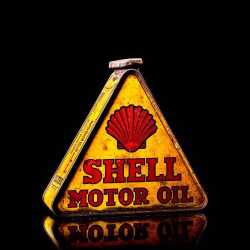 Extremely rare and unique vintage Shell triangular oil can from 1900–1950, featuring red and yellow accents and the classic Shell logo, including a rare shell branding. This antique three-sided tin is displayed in a studio setting against a solid black background.