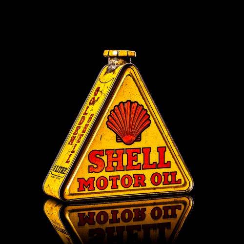 Extremely rare and unique vintage Shell triangular oil can from 1900–1950, featuring red and yellow accents and the classic Shell logo, including a rare shell branding. This antique three-sided tin is displayed in a studio setting against a solid black background.