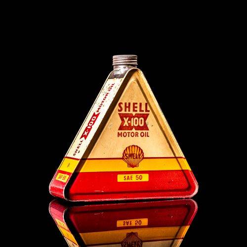 Vintage Shell oil cans with red and yellow branding from the 1900-1920 old logo Vintage Shell oil cans from 1900-19255, featuring the old logo. The photo showcases an antique tin red with yellow accents, displaying the historic Shell emblem. Shot in a studio against a solid black background