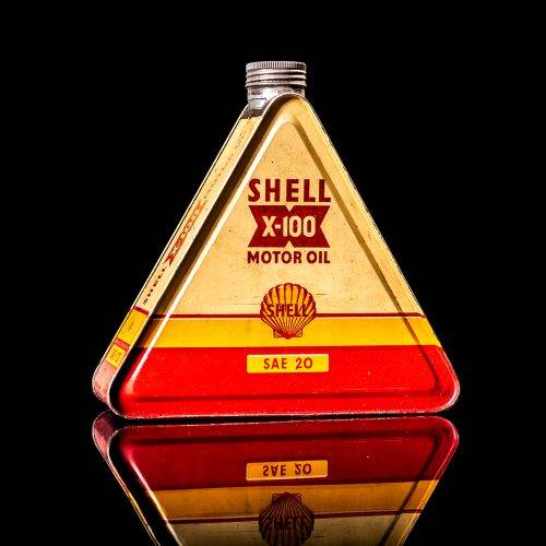 Extremely rare and unique vintage Shell triangular oil can from 1900–1950, featuring red and yellow accents and the classic Shell logo, including a rare shell branding. This antique three-sided tin is displayed in a studio setting against a solid black background.