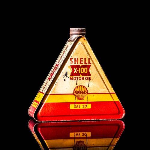 Vintage Shell oil cans with red and yellow branding from the 1900-1920 old logo Vintage Shell oil cans from 1900-19255, featuring the old logo. The photo showcases an antique tin red with yellow accents, displaying the historic Shell emblem. Shot in a studio against a solid black background